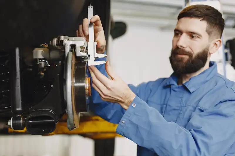 Technician using a 3D wheel alignment system in a modern auto workshop